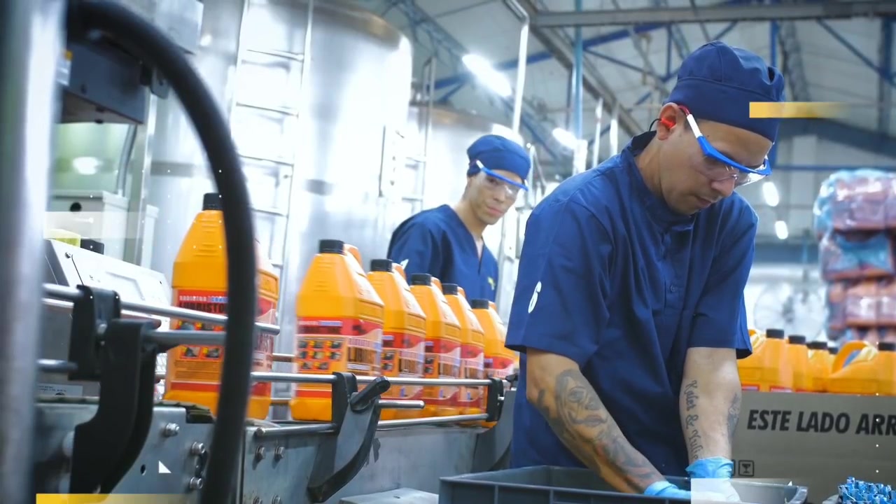 Colaboradores en la línea de producción de Lubristone, junto a sus envases naranjas.