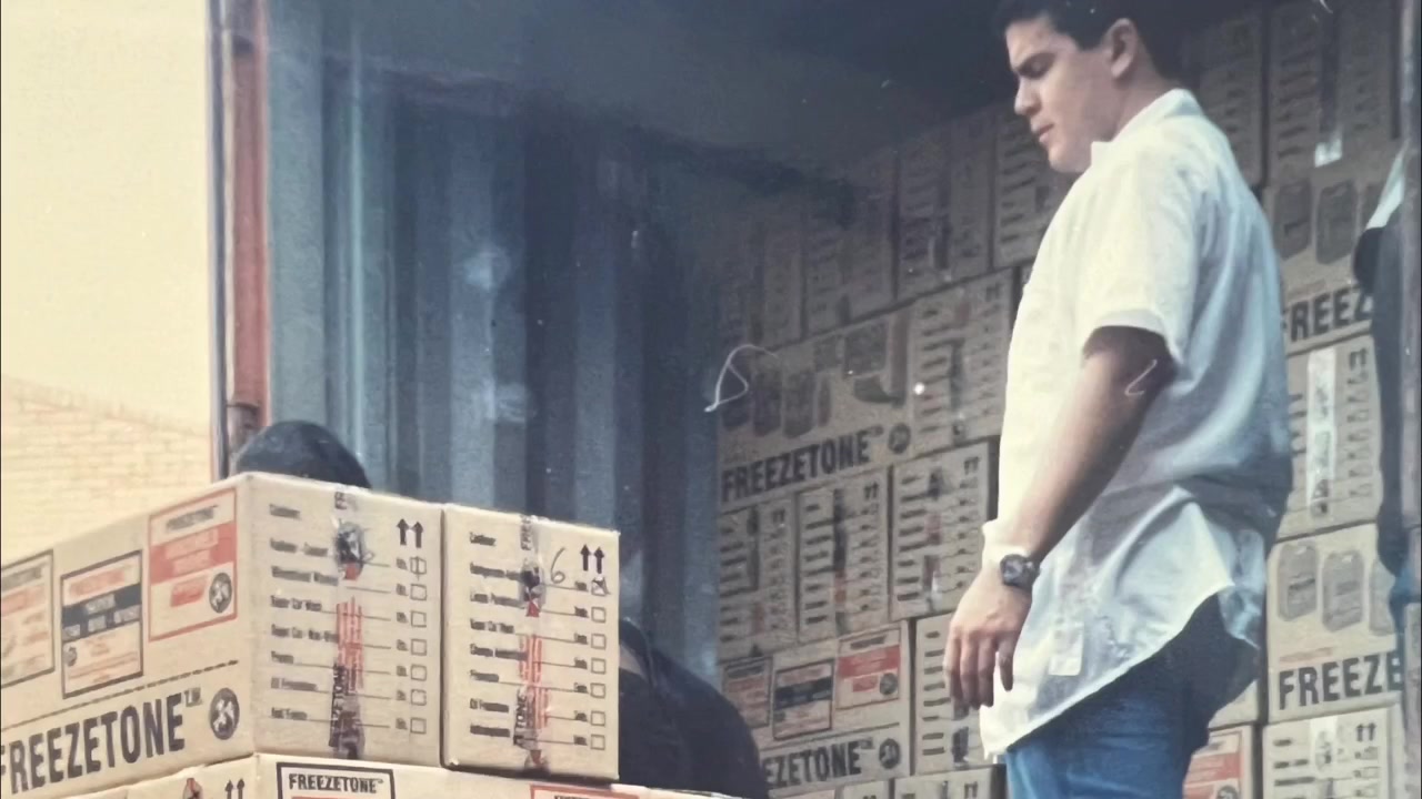 Fotografía antigua de un hombre entre cajas de productos en una bodega.