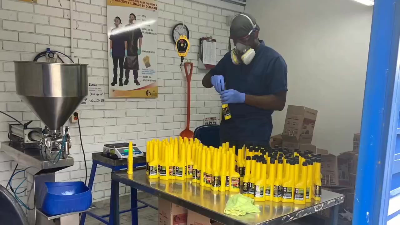 Escena de archivo con un trabajador preparando envases amarillos en una mesa de producción.