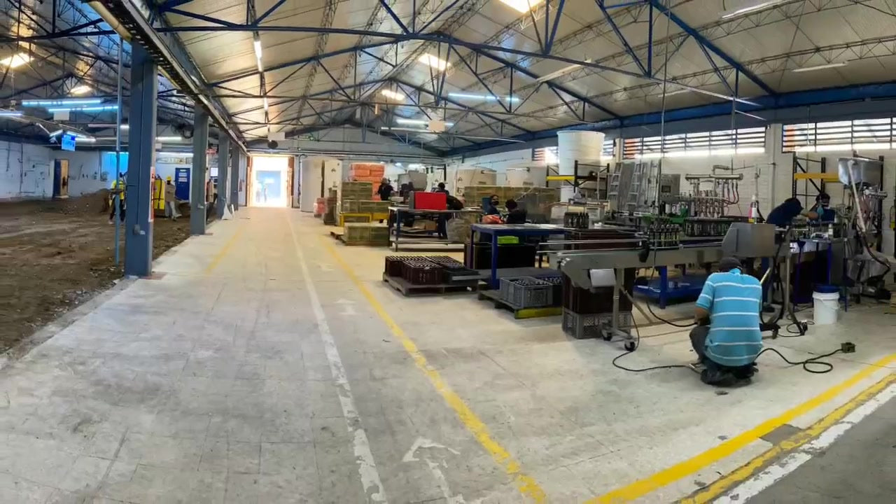 Interior de la planta con líneas de producción, maquinaria y colaboradores.